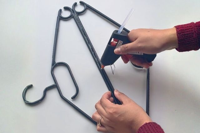 Zwei Kleiderbügel werden mit Heißkleber fixiert.